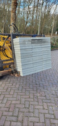 Straatwerk waarbij tegels machinaal worden bijgezet met een klem